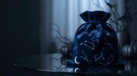 Mystical drawstring pouch with constellation patterns sits on dark surface surrounded by bare branches creating magical witchcraft atmosphere for spiritual practices.