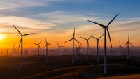 Wind turbines generating renewable energy at sunset with dramatic sky and rolling hills landscape for sustainable power concepts.