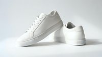 White leather low-top sneakers pair on light background, minimalist casual footwear for fashion, lifestyle, and retail design projects.