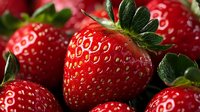 Fresh ripe strawberries with green leaves close up macro shot showing detailed texture and natural pattern of red berries in soft lighting.