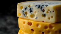 Artisan cheese varieties with holes stacked together showing texture and craftsmanship for gourmet food photography and culinary marketing materials.