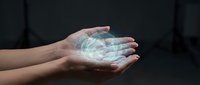Young adult with medium skin tone holding glowing digital holographic data visualization in open palm against dark background, representing technology, innovation, and future digital solutions.