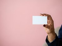 Male hand holding blank white business card against pink background. Isolated on solid color for corporate branding and marketing design use.