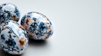 Decorative Easter eggs with delicate floral pattern in blue and copper tones on white porcelain background. Traditional holiday decoration with elegant botanical design.