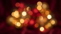 Abstract bokeh lights background with warm golden and red glowing circles creating festive atmosphere for holiday celebrations and decorative projects.
