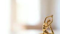 Golden trophy figure in dynamic pose on clean white background with soft lighting for awards ceremonies and achievement recognition.