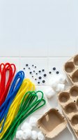 Colorful craft supplies with pipe cleaners, cotton balls, googly eyes and egg carton on white surface for creative DIY projects and children activities.