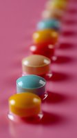Colorful round pills arranged in diagonal line on pink background with selective focus and shallow depth of field, pharmaceutical concept.