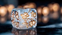 Frosted glass cube with delicate floral pattern illuminated by warm bokeh lights on dark reflective surface, creating magical atmospheric mood.