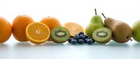 Fresh colorful fruits arranged on white surface including oranges, kiwi slices, blueberries and pears for healthy eating and nutrition concepts.