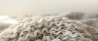 Cozy knitted wool sweater with cable pattern in neutral beige tones, soft textile background for fashion and comfort concepts.