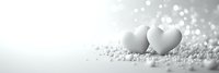 Two white hearts on glittering silver background with bokeh lights and copy space, romantic minimalist composition in monochrome style for valentines day or wedding.