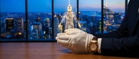 Businessman hand holding glowing human figure over city skyline at dusk. Business leadership, mentorship and human resources management concept for corporate presentations.