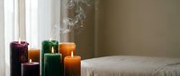 Colorful burning candles with smoke creating peaceful ambiance near window. Relaxation, meditation, aromatherapy and home decor concept for wellness lifestyle.