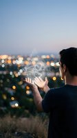 Young Caucasian man holding smoke or magic energy between his hands against blurred city lights bokeh at dusk, mystical urban concept.