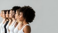 Diverse group of women in profile showing multicultural beauty and unity in white tops against neutral background for empowerment campaigns.