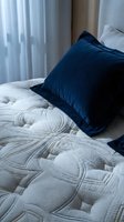 Navy blue velvet pillow on white quilted bedding with sheer curtains in background. Cozy bedroom interior design and home decor styling for residential spaces.
