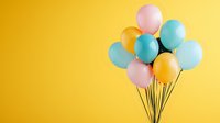 Festive pastel and gold balloons bunch floating against vibrant yellow background, minimal party decoration setup for celebration and events.