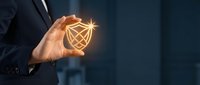 Businessman holding glowing geometric heart symbol in cupped hands representing love, care, healthcare, charity, and emotional connection in corporate environment.