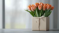 Fresh coral tulips arranged in beige square box with twine bow on light background, elegant floral composition for home decor and special occasions.
