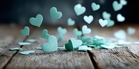 Mint green paper hearts scattered on rustic wooden surface, creating romantic atmosphere for wedding decorations, Valentine's day cards, or love-themed projects.