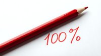 Red pencil lying next to handwritten 100% text on white background, symbolizing perfect score, full achievement, and complete success.