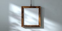 Empty wooden picture frame hanging on light gray wall with natural shadow play, creating minimalist home decor element for gallery or exhibition space.