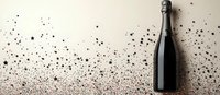 Champagne bottle with scattered black glitter and stars on beige background, festive celebration concept for luxury events and special occasions.