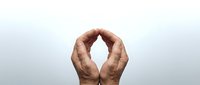 Elderly male hands forming a protective arch gesture on a light gray background, symbolizing care, shelter, and support.