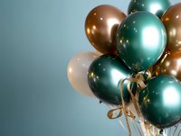 Festive balloon bouquet with metallic green and gold balloons tied with ribbon against blue background for party celebrations and special events.