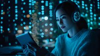 Young Asian woman in cozy sweater using tablet device at night, illuminated by blue bokeh lights while wearing wireless headphones, creating atmospheric mood.