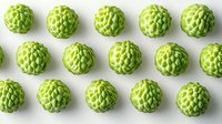 Fresh green custard apples arranged in neat rows on white background, organic tropical fruit pattern showing detailed texture and symmetrical composition.