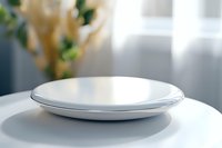 Empty white ceramic plate on modern kitchen counter with soft natural lighting and blurred home interior background for food presentation.
