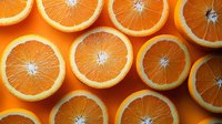 Fresh juicy orange slices arranged in rows on vibrant orange background, creating geometric pattern. Natural citrus fruit composition for healthy lifestyle concept.