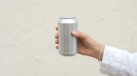 Hand holding blank silver aluminum can against light wall, mockup for beverage branding, soda or beer packaging design concept.