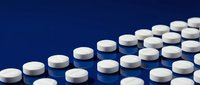 White round pills arranged in arrow pattern on reflective blue surface, symbolizing medical treatment, pharmacy, and healthcare concepts.