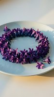 Purple lilac flowers arranged in circular wreath on ceramic plate for spring decoration and crafting projects.