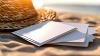 Blank postcards and straw hat on sandy beach at sunset. Summer vacation correspondence mockup with warm golden light and coastal backdrop for travel memories.