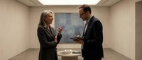 Professional business meeting between confident blonde woman and businessman in modern office conference room discussing strategy and collaboration.