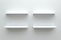 Empty white floating shelves mounted on light gray wall, minimalist modern interior design element for product display and home organization.