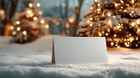 Blank greeting card in snow with festive Christmas trees and warm bokeh lights creating magical winter holiday atmosphere in background.