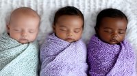 Sleeping newborns wrapped in knitted blankets showing diversity. Three peaceful babies in mint and purple swaddles lying together on soft textured background.