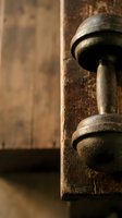 Vintage dumbbell with textured grip resting on weathered wooden surface, showcasing aged metal and rustic fitness equipment for gym, wellness, and strength training concepts.
