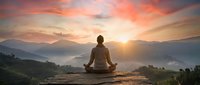 Woman meditating in lotus pose on mountain peak at sunrise with dramatic orange sky and layered mountain ranges creating peaceful spiritual atmosphere.