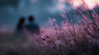 Romantic couple silhouette in soft focus background with delicate wildflowers in foreground creating dreamy bokeh effect at sunset for love concepts.