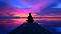 Silhouette of person meditating on wooden pier at sunset, dramatic purple and pink sky reflecting in calm lake waters, peaceful mindfulness scene.