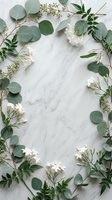 Elegant eucalyptus leaves and white flowers arranged in oval frame on marble background with copy space for wedding invitations and botanical designs.