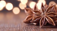 Star anise pods on rustic wooden surface with soft bokeh lights in background creating warm festive atmosphere for seasonal cooking and decoration.