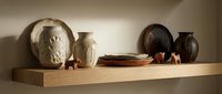 Wooden shelf displaying collection of ceramic vessels, clay pots, and sculptural busts in neutral earth tones, suitable for interior design and home decor projects.