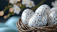 Speckled white Easter eggs with brown dots in rustic wicker basket against blurred spring blossom background. Festive holiday decoration concept.
